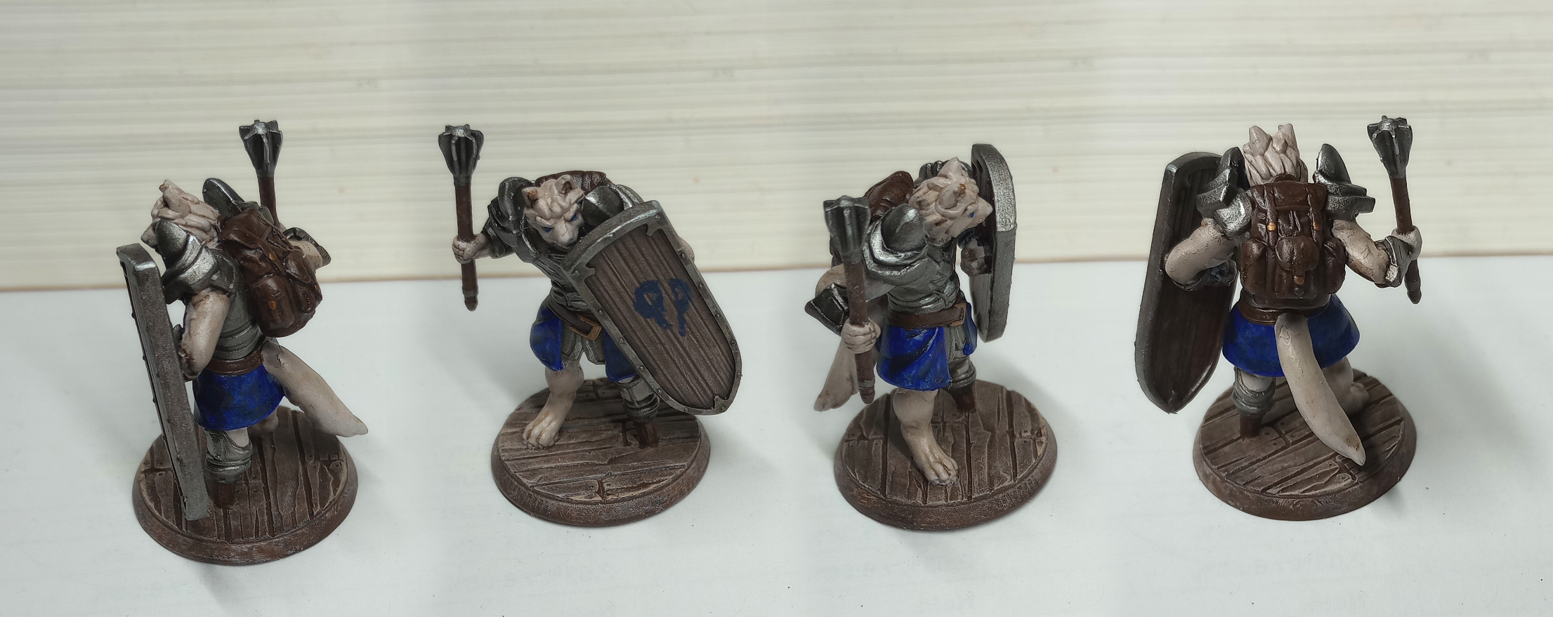 A figurine of a male gnoll with light fur in plate armor with a mace and a tower shield.